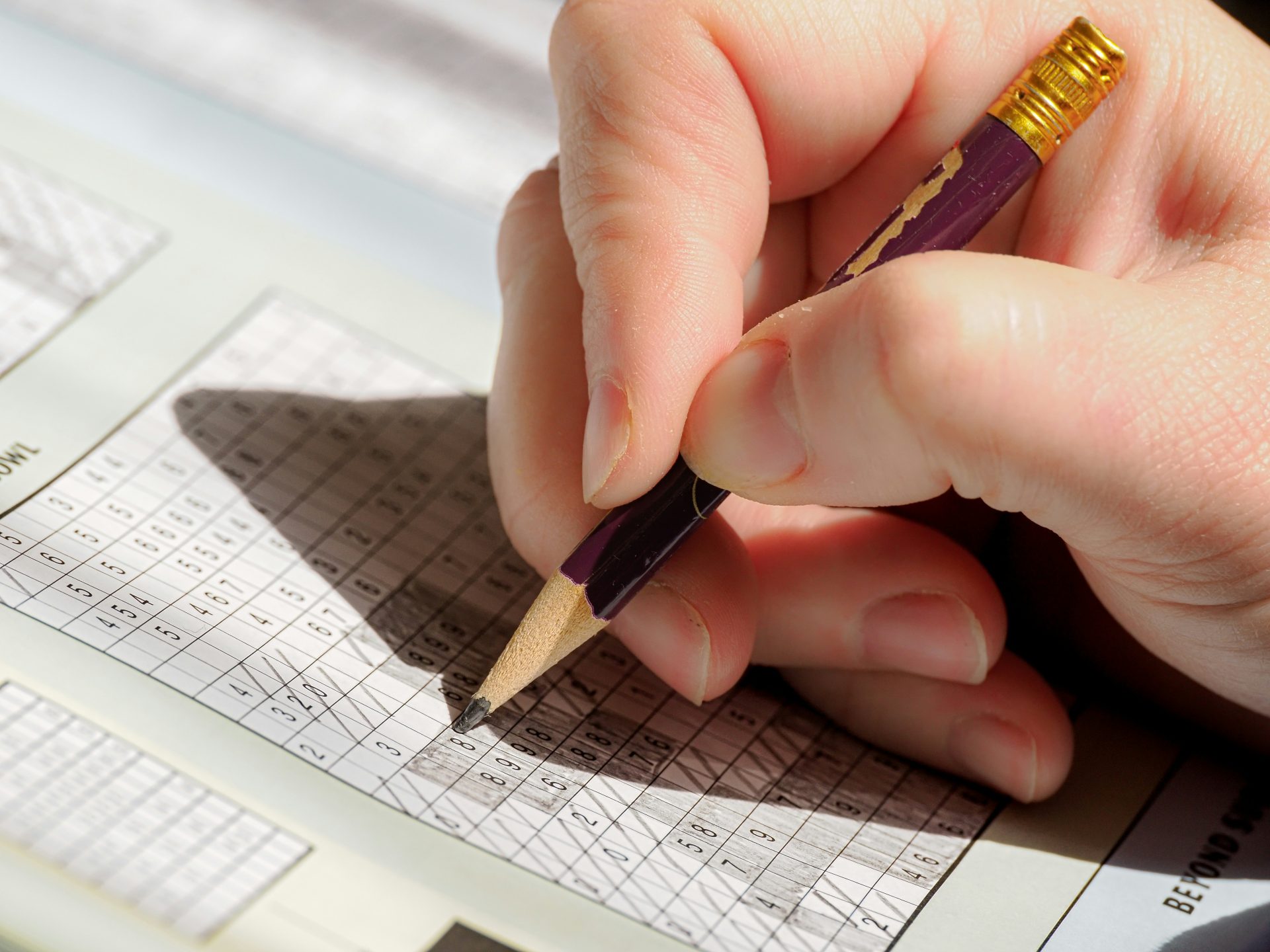 Une personne tenant un crayon et écrivant sur une feuille de papier