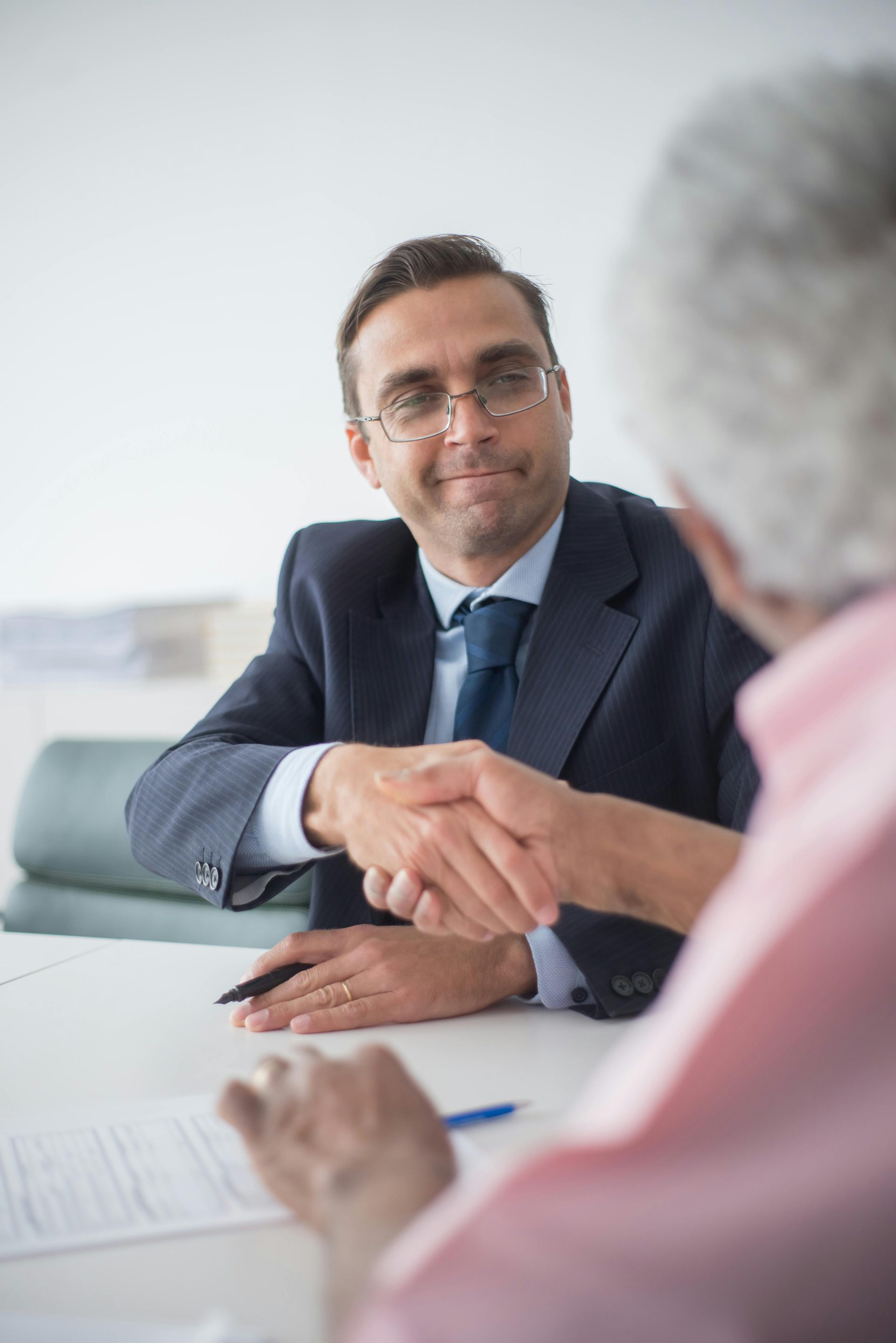 Two businessmen shaking hands in an office setting, symbolizing a successful business deal.
