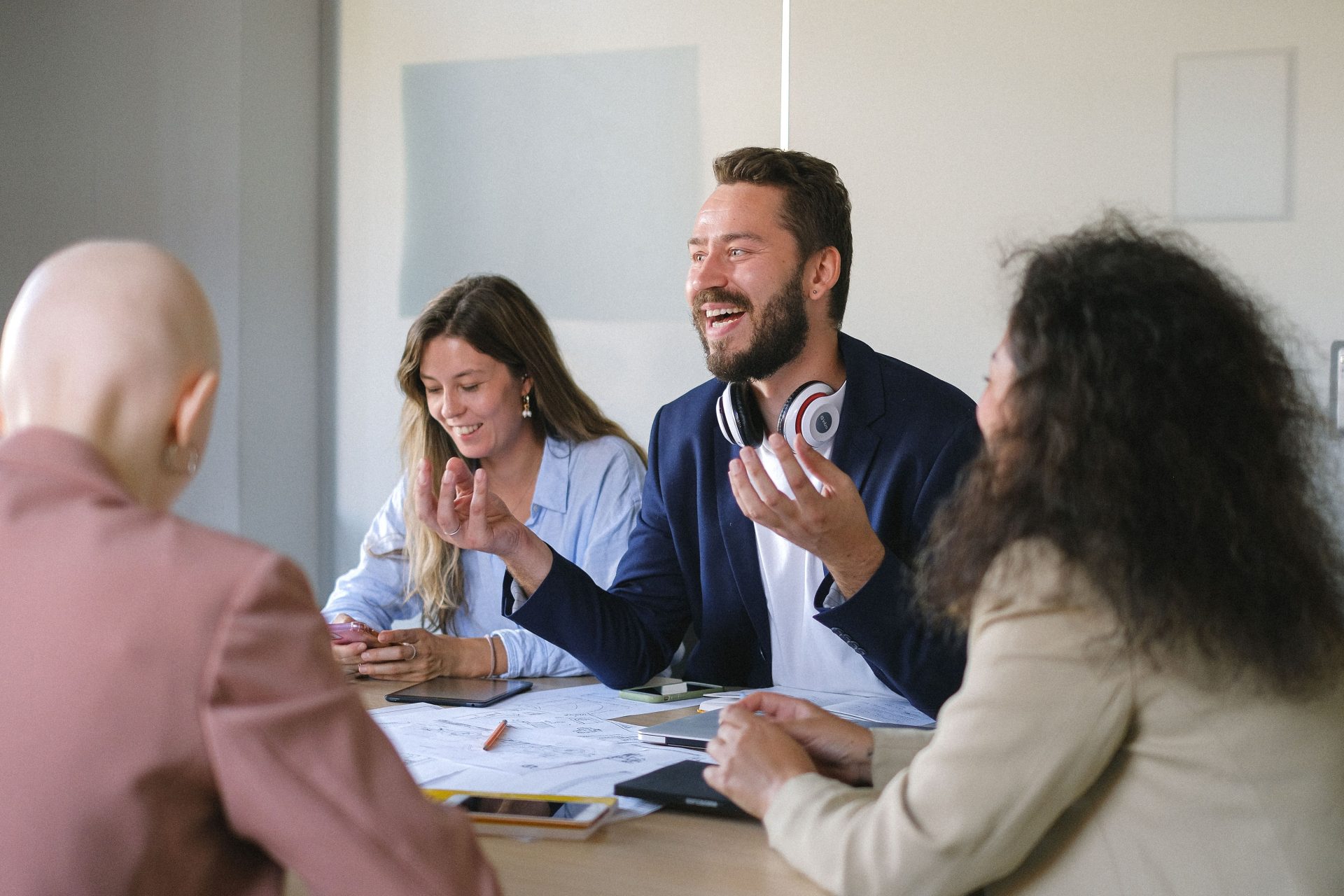 Un groupe de collègues joyeux discutant et échangeant des avis autour d'une table lors d'une réunion dans des bureaux.